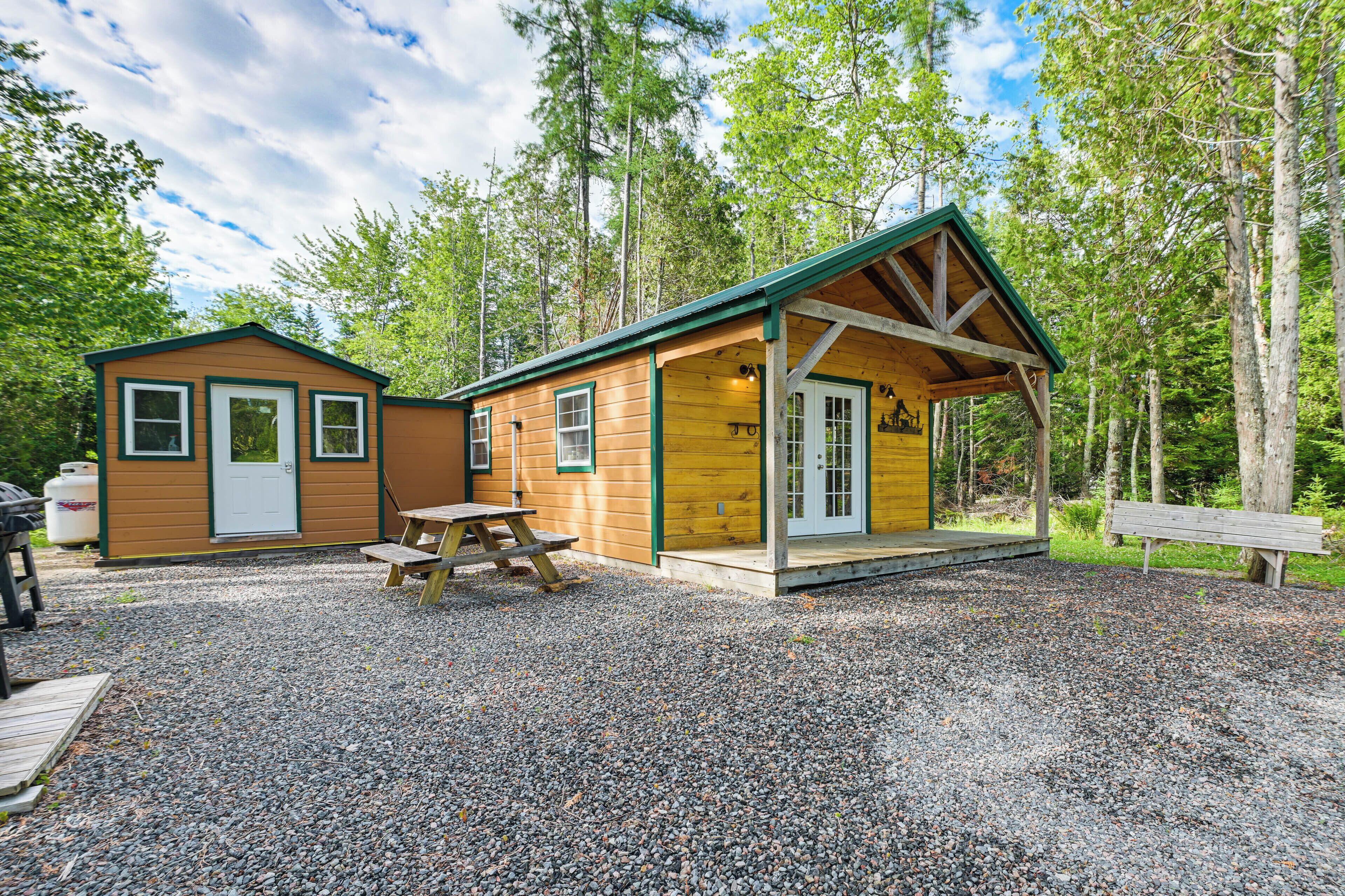 A cabin with a covered porch, a picnic table, and a bench.