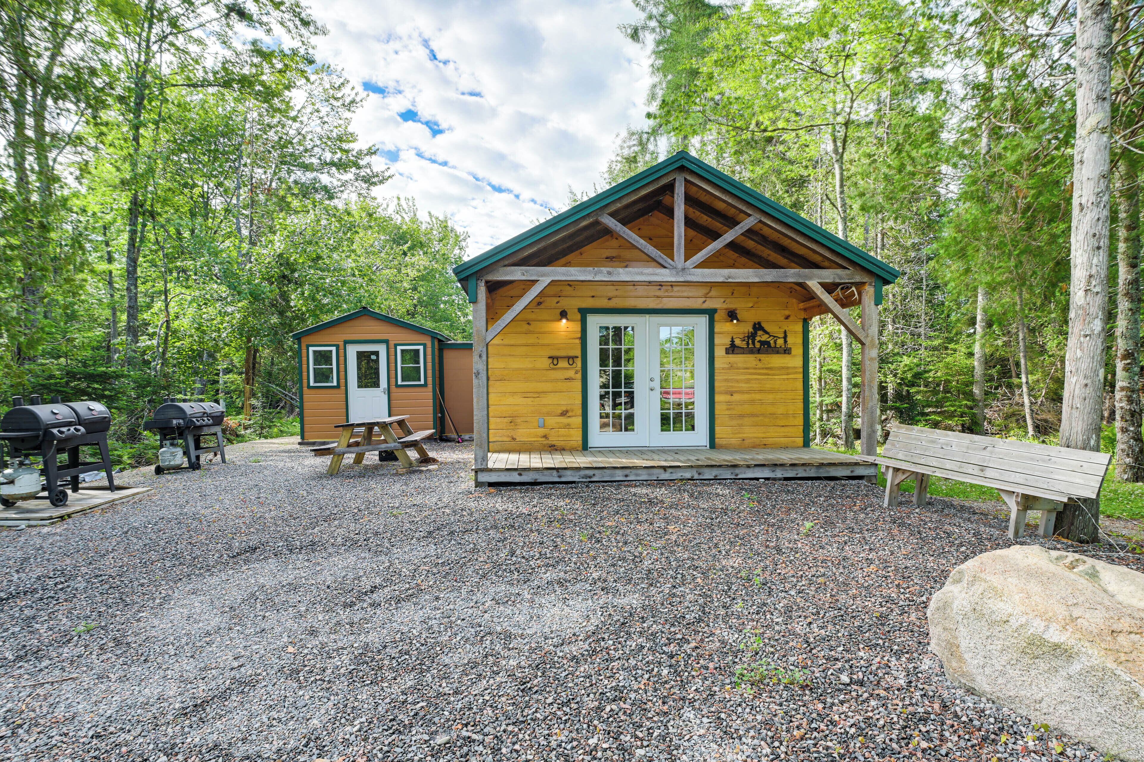 A rustic cabin with a wooden exterior, a porch, and a grill area.