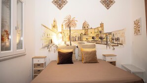 A bedroom with a bed, two nightstands, a window, and a wall mural of a cityscape. - Apartment in the very center of Palermo, within walking distance of the famous 4 canti. (Palermo)