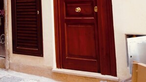 A wooden door with a brass handle and a small window with shutters to the left. - Apartment in the very center of Palermo, within walking distance of the famous 4 canti. (Palermo)