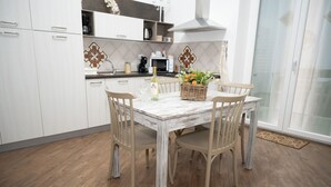 A dining area with a wooden table and chairs, a decorative basket, and a bottle of wine. - Apartment in the very center of Palermo, within walking distance of the famous 4 canti. (Palermo)