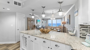 A spacious kitchen with a large island, white cabinetry, and pendant lighting. - Update 2Br Beachfront Condo - Balcony View, Pool,  and Tram. Steps to Beach! (Miramar Beach)