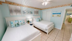 A bedroom with two beds, a nightstand, and a ceiling fan. - Venus 116 - Beach side 1 BR steps to the Gulf (Fort Walton Beach)