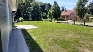 A residential backyard with a lawn, a patio area, and a wooden fence. - Ankerplatz in Idyllischer Umgebung und Nähe zum Bernsteinsee (Wiefelstede)