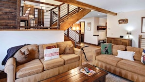 A spacious living room with two beige sofas, a wooden coffee table, and a staircase leading to an upper level. - Potato Patch Luxury 4 Bedroom Townhome - Vail Point (Vail)