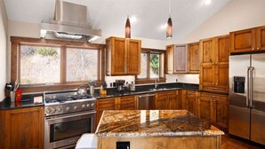 A modern kitchen with wooden cabinets, stainless steel appliances, and a granite island. - Potato Patch Luxury 4 Bedroom Townhome - Vail Point (Vail)