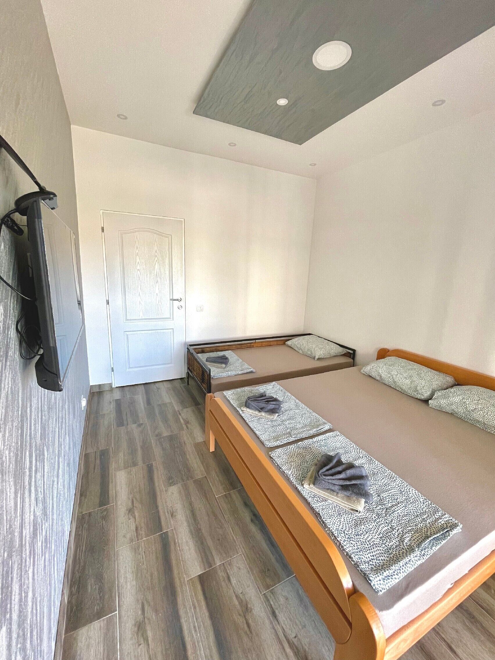 Ein modernes Schlafzimmer mit einem hölzernen Bett, einem flachbildfernseher an der Wand und einer Tür zu einem anderen Raum.