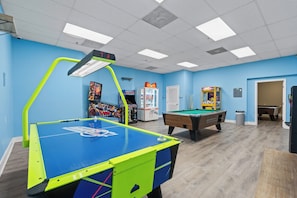 A recreational room with a foosball table, pool table, and arcade games.
