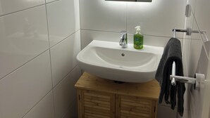 Une salle de bain avec un lavabo blanc, un miroir et un meuble en bois.
