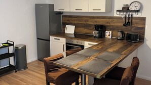 Une cuisine moderne dotée d’un îlot central en bois, d’appareils électroménagers en acier inoxydable et d’un luminaire suspendu.