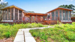 A modern wooden cabin with large windows and a covered porch. - Wild Candy Farm - Breezeway Haus (Wimberley)
