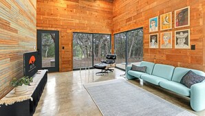 Un intérieur moderne avec des murs en bois, un canapé, un fauteuil et des œuvres d’art accrochées au mur.