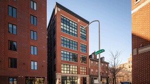 A multi-story brick building with large windows and a street sign indicating 'N. American St'. - Sosuite | 1 Bedroom Apt w Shared Roofdeck (Philadelphia)