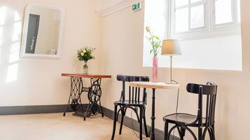 A room with a chandelier, a table with chairs, a vase with flowers, and a window with natural light.