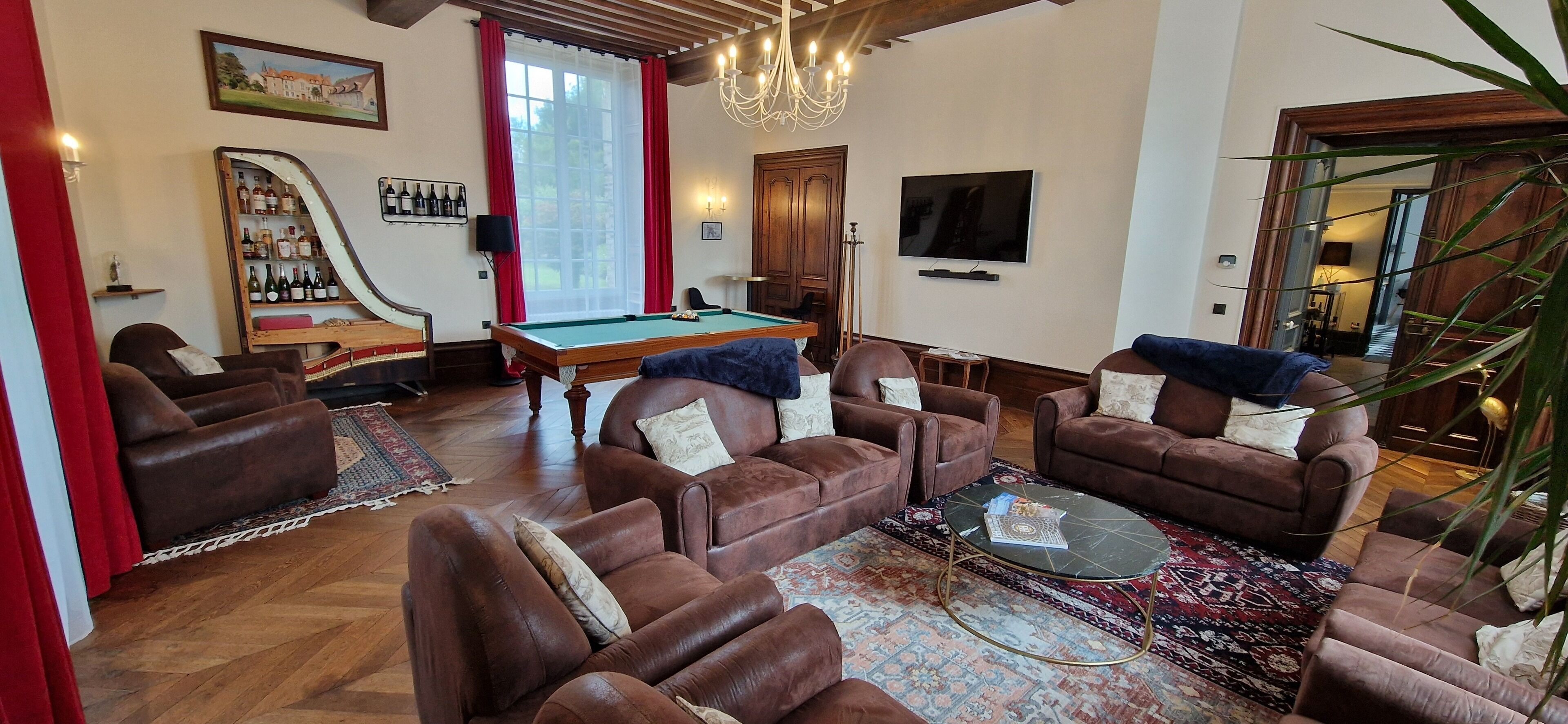 Una sala de estar con sofás de cuero, una mesa de billar, una estantería y un televisor.