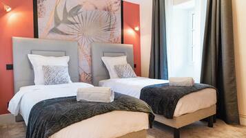 Een hotelkamer met twee bedden, een groot abstract kunstwerk aan de muur en uitzicht op het landschap door het raam.