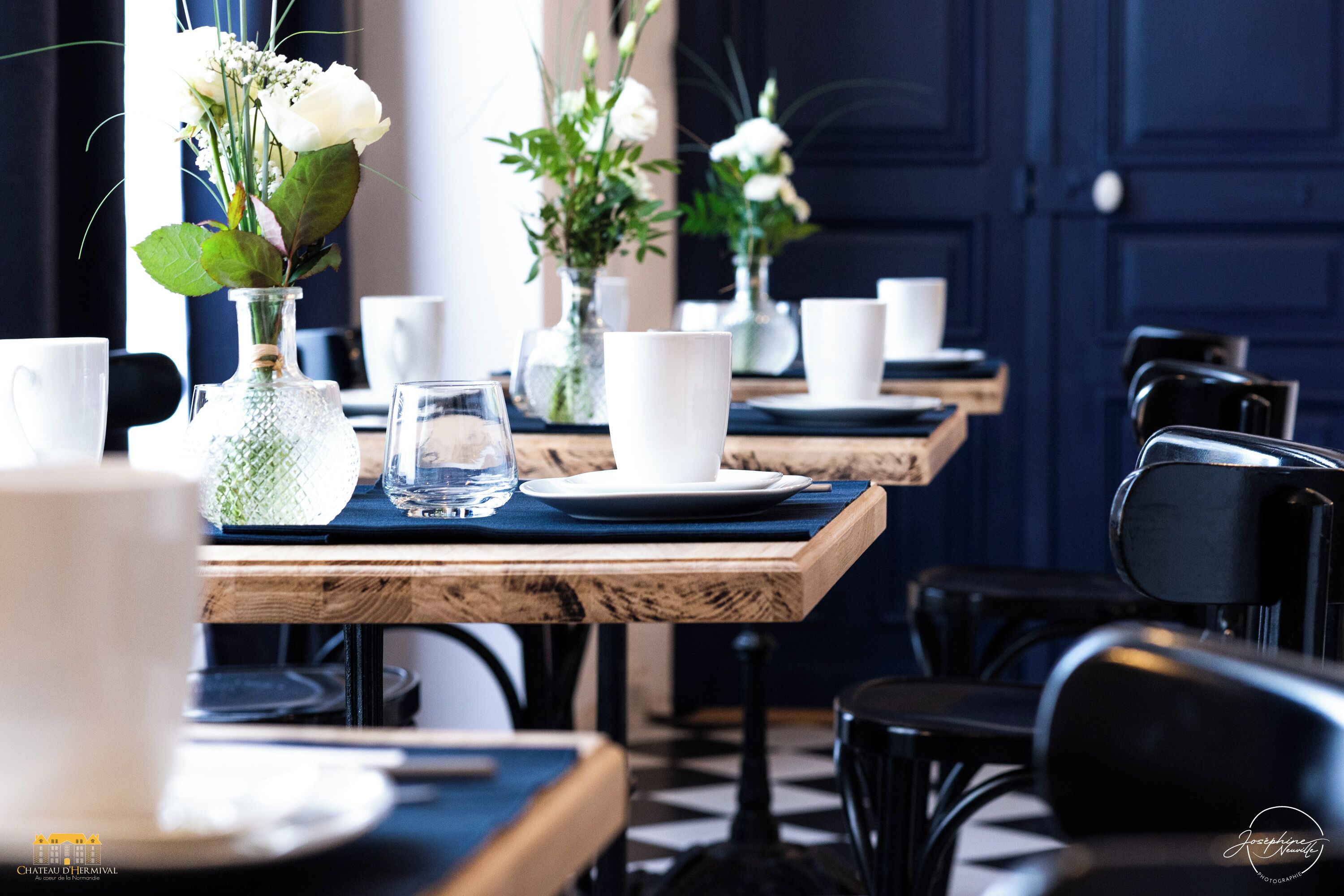 A dining area with wooden tables, white plates, and clear glassware.