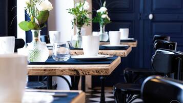 A dining area with wooden tables, white plates, and clear glassware.