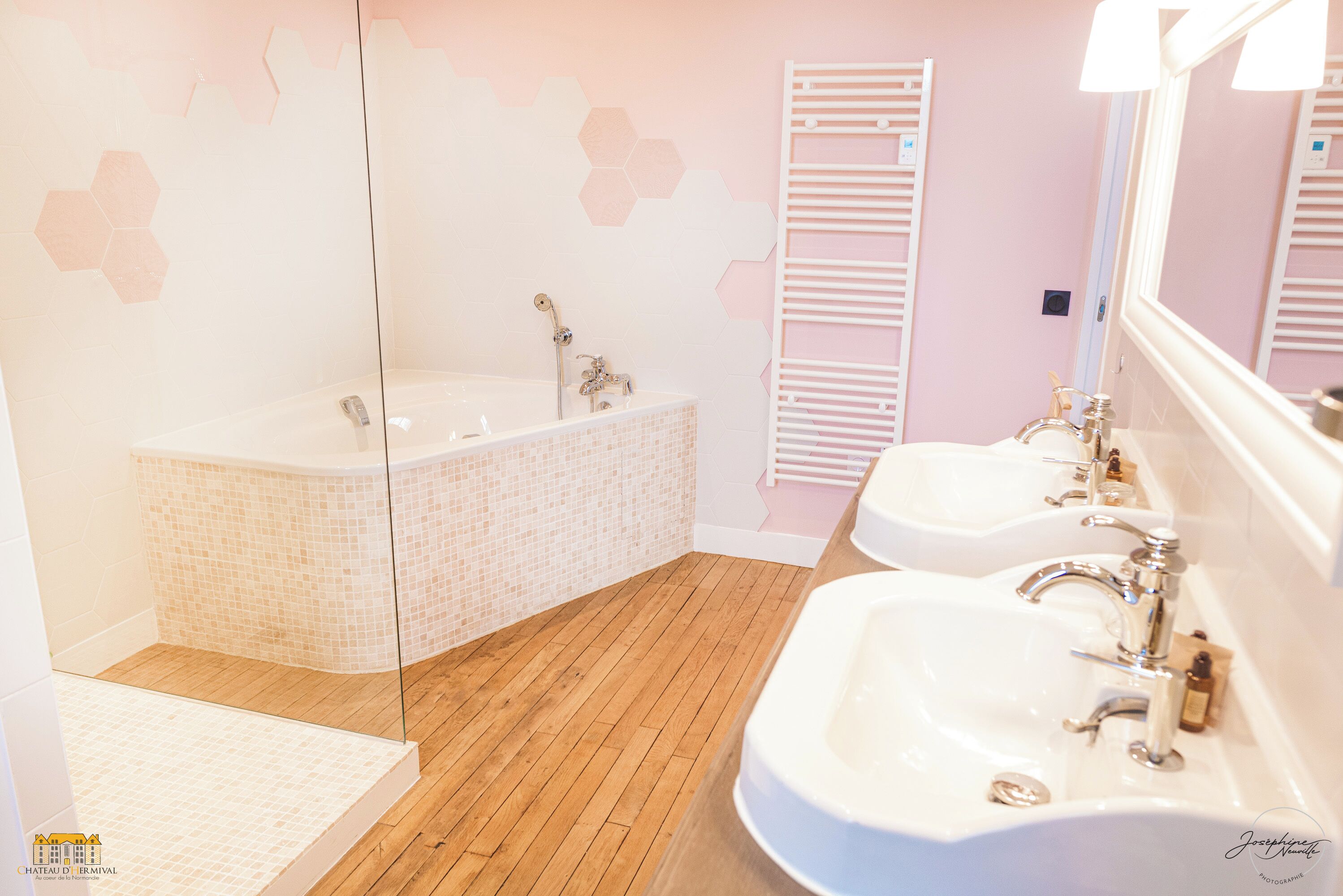 Un baño con una bañera grande, dos lavamanos y un espejo.
