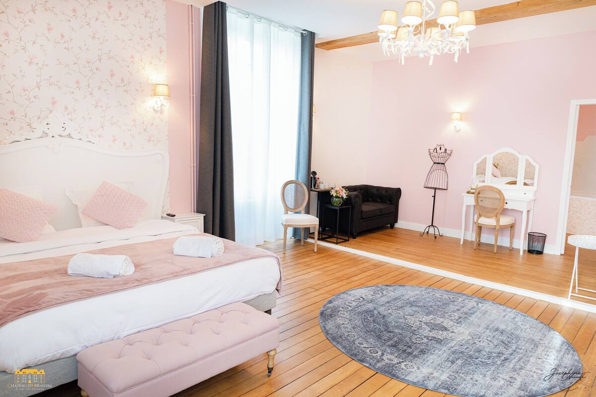 A bedroom with a large bed, a dresser, a vanity, and a chandelier.