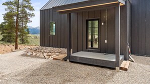 Una cabaña moderna con fachada de madera, un porche y vistas a la montaña.