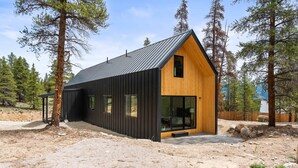 Una cabaña moderna con techo inclinado, ventanas grandes y fachada de madera.