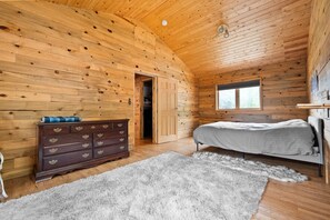 A wooden cabin bedroom with a bed, dresser, and a window. - Hwy 91 Log Cabin — 2BR/2BA, Fireplace, Mtn Views, Sleeps 4 (Leadville)