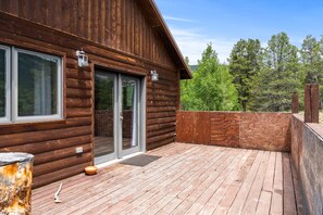 A wooden cabin with a deck, large windows, and a door with glass panels. - Hwy 91 Log Cabin — 2BR/2BA, Fireplace, Mtn Views, Sleeps 4 (Leadville)