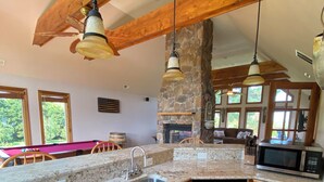 A kitchen with granite countertops, wooden cabinets, a built-in wine cooler, and a stone fireplace.