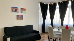 A room with a black sofa, a dining table with chairs, and two windows with black curtains. - Like At Home Venice Mestre, bright, family and private parking place. (Venezia)