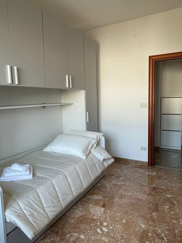 A bedroom with a bed, a wardrobe, and a bathroom visible through an open door.