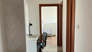A hallway with a desk and office chair, a trash bin, and a view into another room. - Like At Home Venice Mestre, bright, family and private parking place. (Venezia)