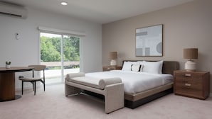 A modern bedroom with a large bed, bedside tables, a desk, and a chair.
