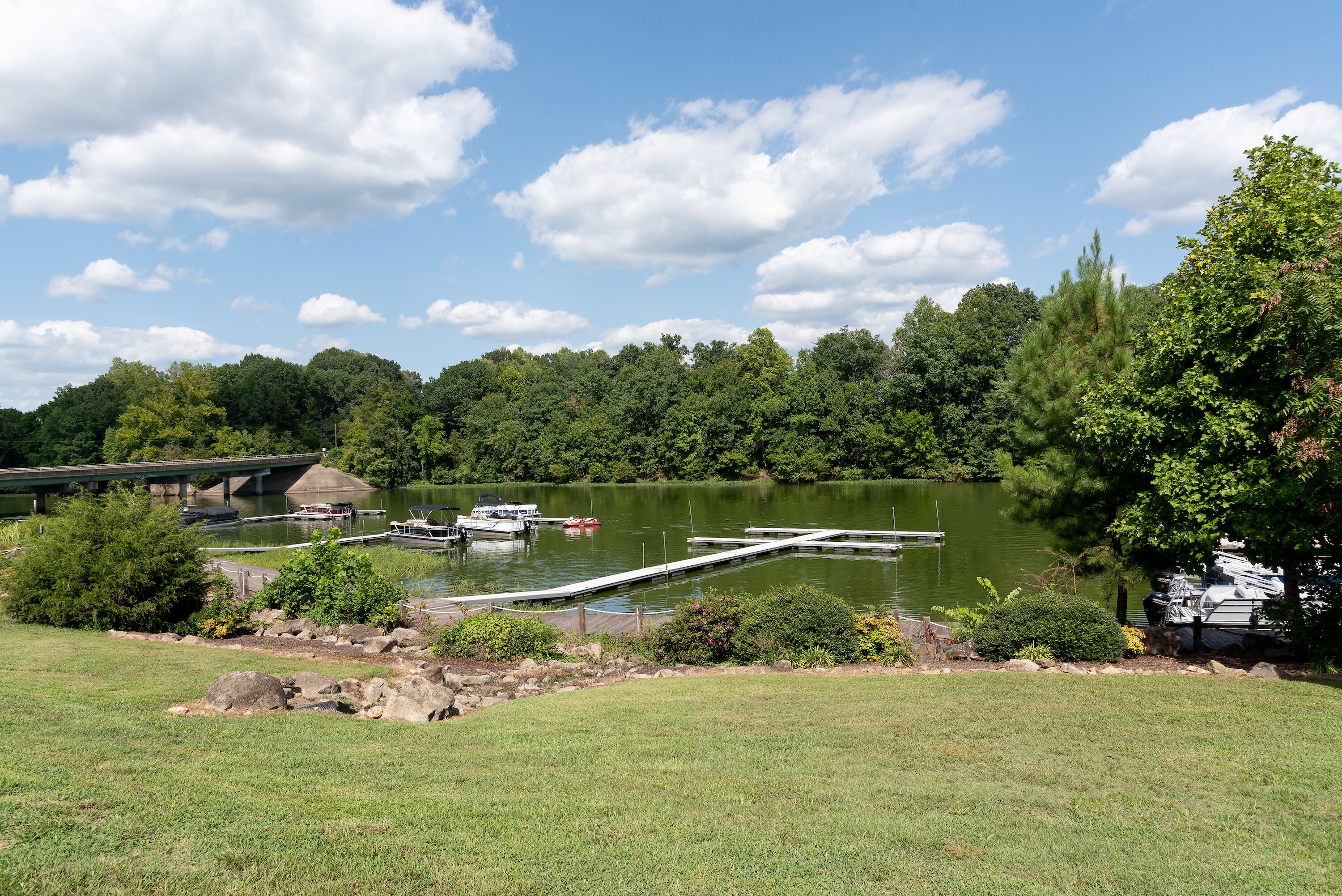 A lakeside view with a dock, boats, and a bridge.