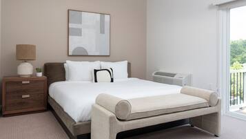 A modern bedroom with a bed, bedside table, lamp, and a large window.