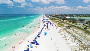 Een strand met een lange rij parasols en mensen.