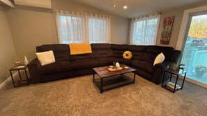 Ein Wohnzimmer mit einem dunkelbraunen Ecksofa, einem Holztisch und einem kleinen Beistelltisch.