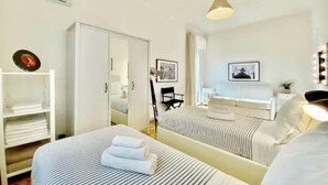 A hotel room with two beds, a wardrobe, a desk, and a mirror. - Luxurious & Spacious Apartment with Unique Amenities near Vatican (Roma)