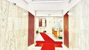 A hotel lobby with marble walls, a red carpet, and a reception desk. - Luxurious & Spacious Apartment with Unique Amenities near Vatican (Roma)