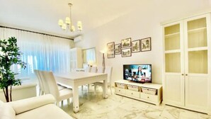 A modern living room with a dining area, a television, and a cabinet. - Luxurious & Spacious Apartment with Unique Amenities near Vatican (Roma)