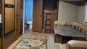 A compact RV interior with a kitchenette, a dining area, and a bathroom. - Camp in style with AC/heat, WIFI, on Main Street, 1 block from Joni's beach (La Pointe)