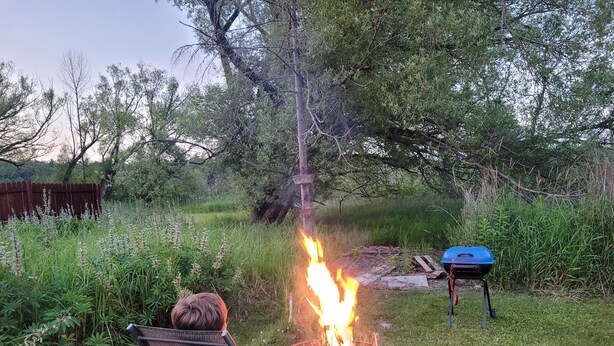 A backyard with a fire pit, a chair, and a grill. - Camp in style with AC/heat, WIFI, on Main Street, 1 block from Joni's beach (La Pointe)