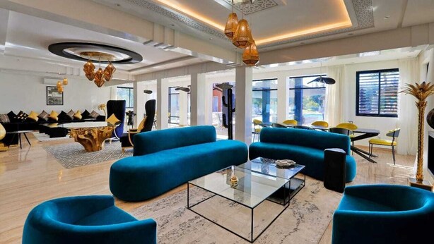 Un vaste espace de vie avec des canapés bleus, une table basse en verre et un piano.