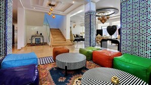 Un hall d’entrée spacieux avec un escalier, des sièges aux couleurs vives et des murs à motifs.