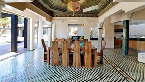 Un espace repas doté d’un sol à motifs, d’une table en bois avec des chaises et d’un plafond orné de décorations complexes.