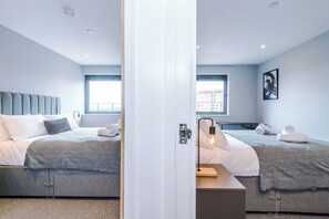 A modern hotel room with two beds, a large window, and a view of the city. - Hilltop Serviced Apartments-Sheffield (Sheffield)