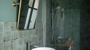 Une salle de bain avec un meuble-lavabo en bois, un lavabo blanc, un miroir et une douche séparée par une paroi de verre.