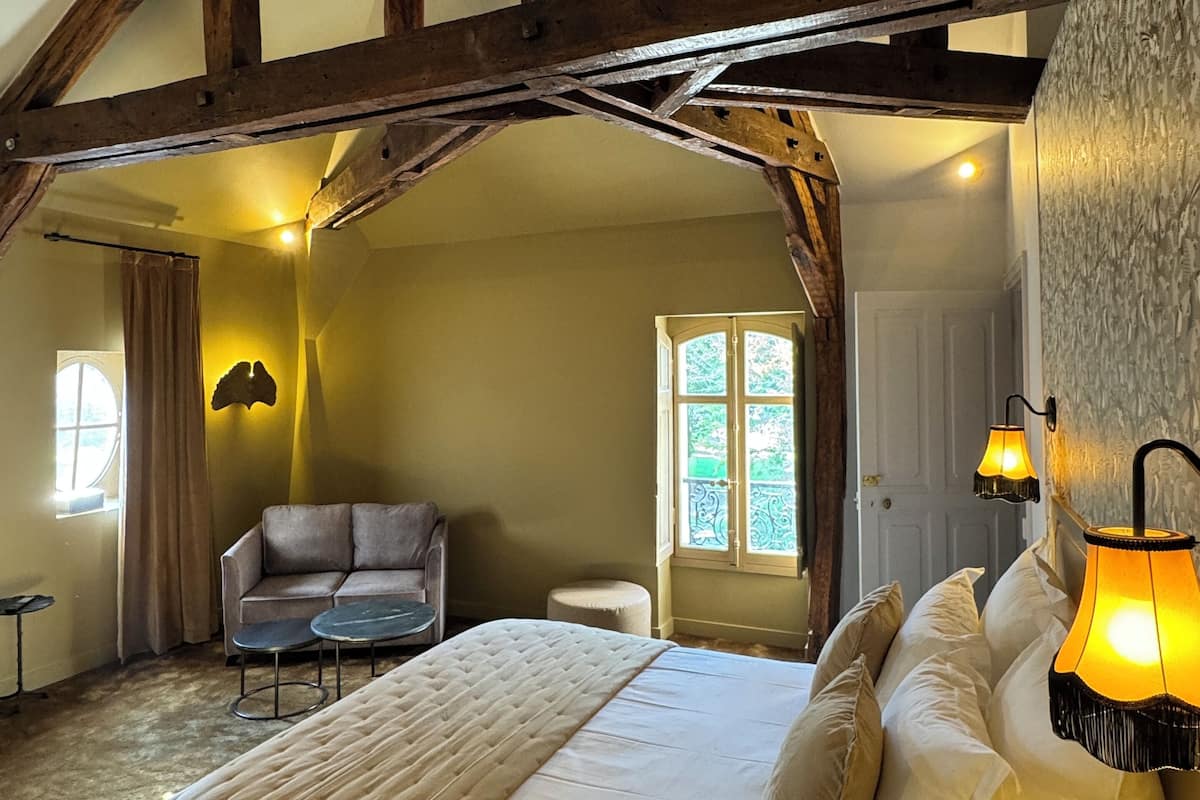 Een slaapkamer met een groot bed, een bank, een bijzettafeltje en een lamp.