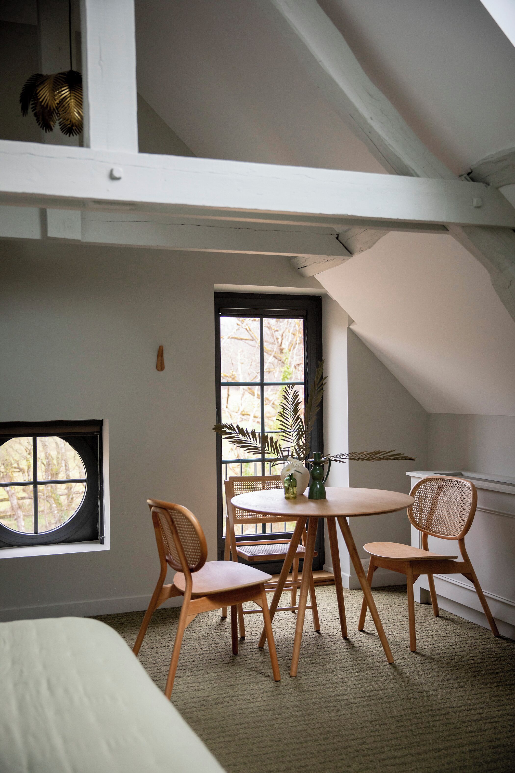 Une pièce avec un plafond haut, une table à manger avec des chaises, une fenêtre et une porte.