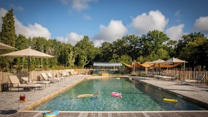 A rectangular swimming pool with clear water, surrounded by lounge chairs and umbrellas, with a wooden deck in the foreground. - Les Hayes en Sologne (Fontaines-en-Sologne)